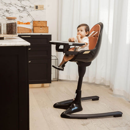 Child sitting in Hot Mom High Chair - Black Gold at a kitchen counter.