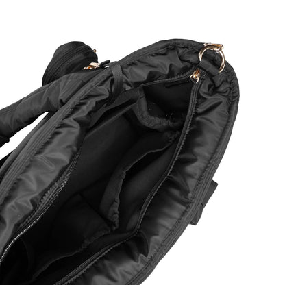 Close-up of an open Luli Bebé Infinite Diaper Bag - Black showing the interior compartments, zipper tracks, and a small gold-tone metal ring hardware on a white background.