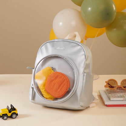 Sunveno Jelly Adventure Backpack - Silver, surrounded by balloons and books on a beige surface.