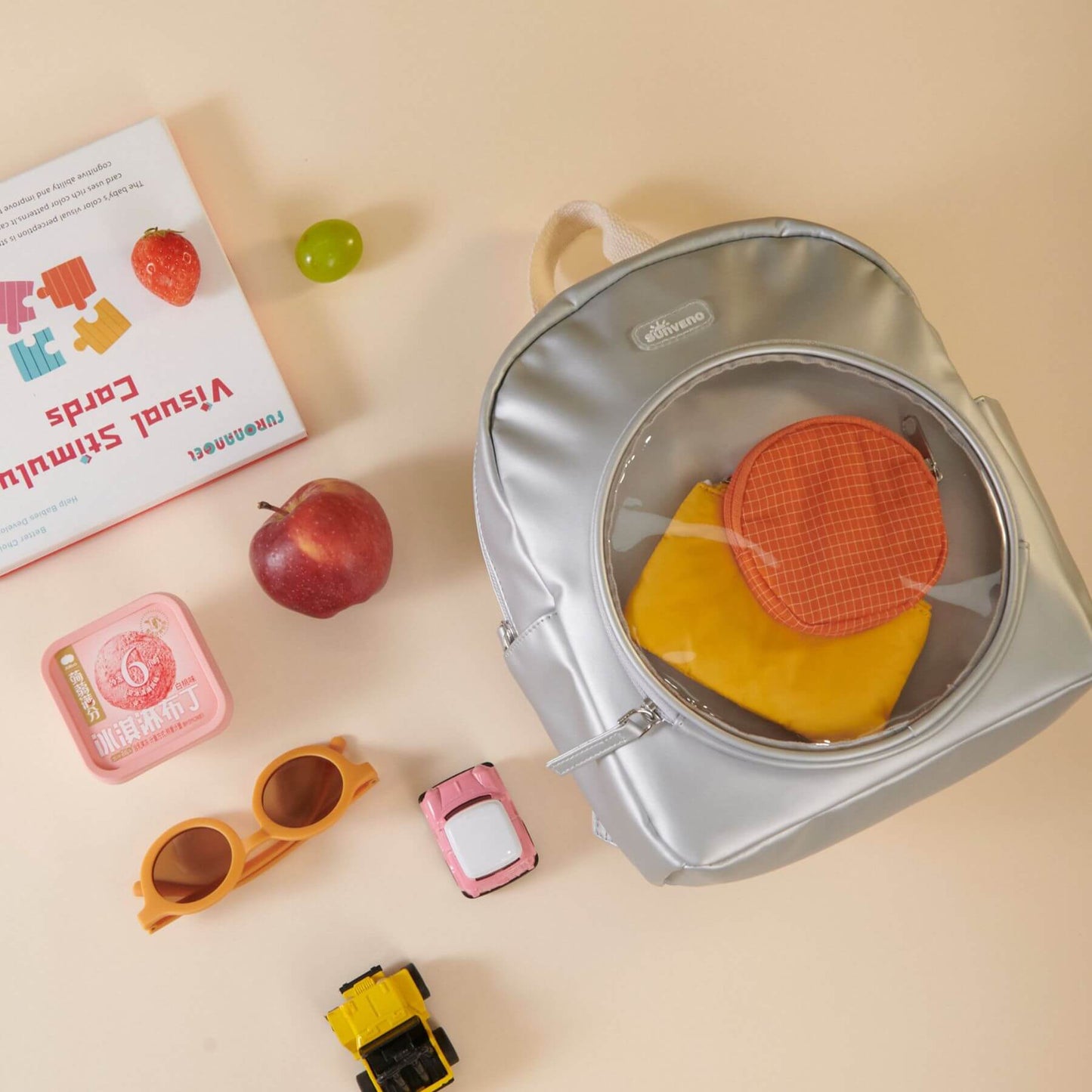 Sunveno Jelly Adventure Backpack - Silver with toys on a beige background