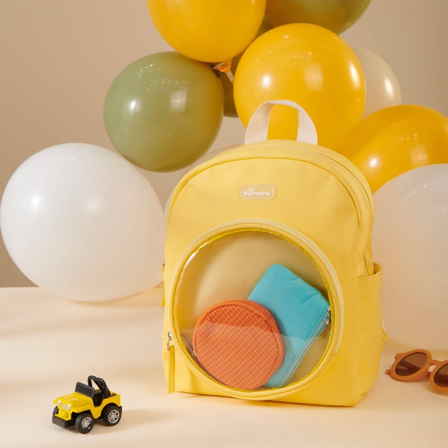 Sunveno Jelly Adventure Backpack - Yellow with toys and a toy car, surrounded by balloons on a beige background