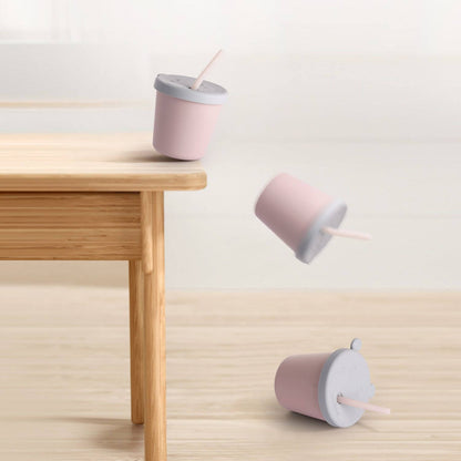 Haakaa Jolly Hippo Silicone Sippy Cup on a wooden table and floor with a light background