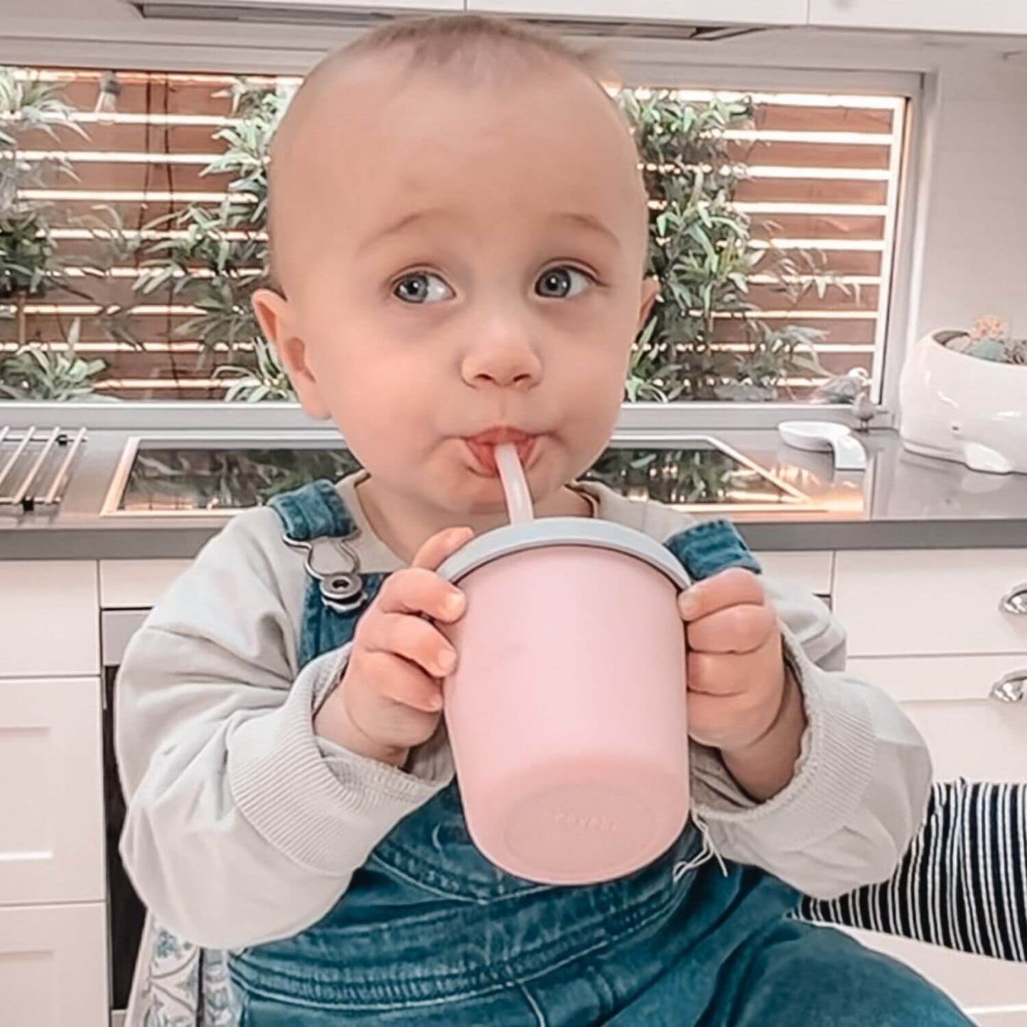 Child drinking from Haakaa Jolly Hippo Silicone Sippy Cup in a kitchen