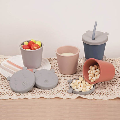 Set of silicone snack cups with lids on a lace tablecloth.