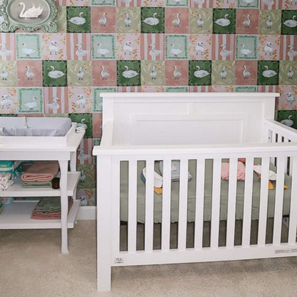 Nursery with white crib and changing table against a patterned wall.