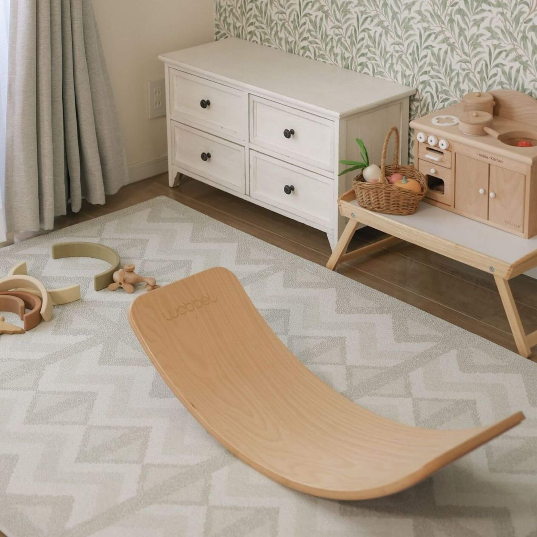 Wooden balance board on Eeveve Kilim Play Mat, Feather Gray with toys and furniture in the background