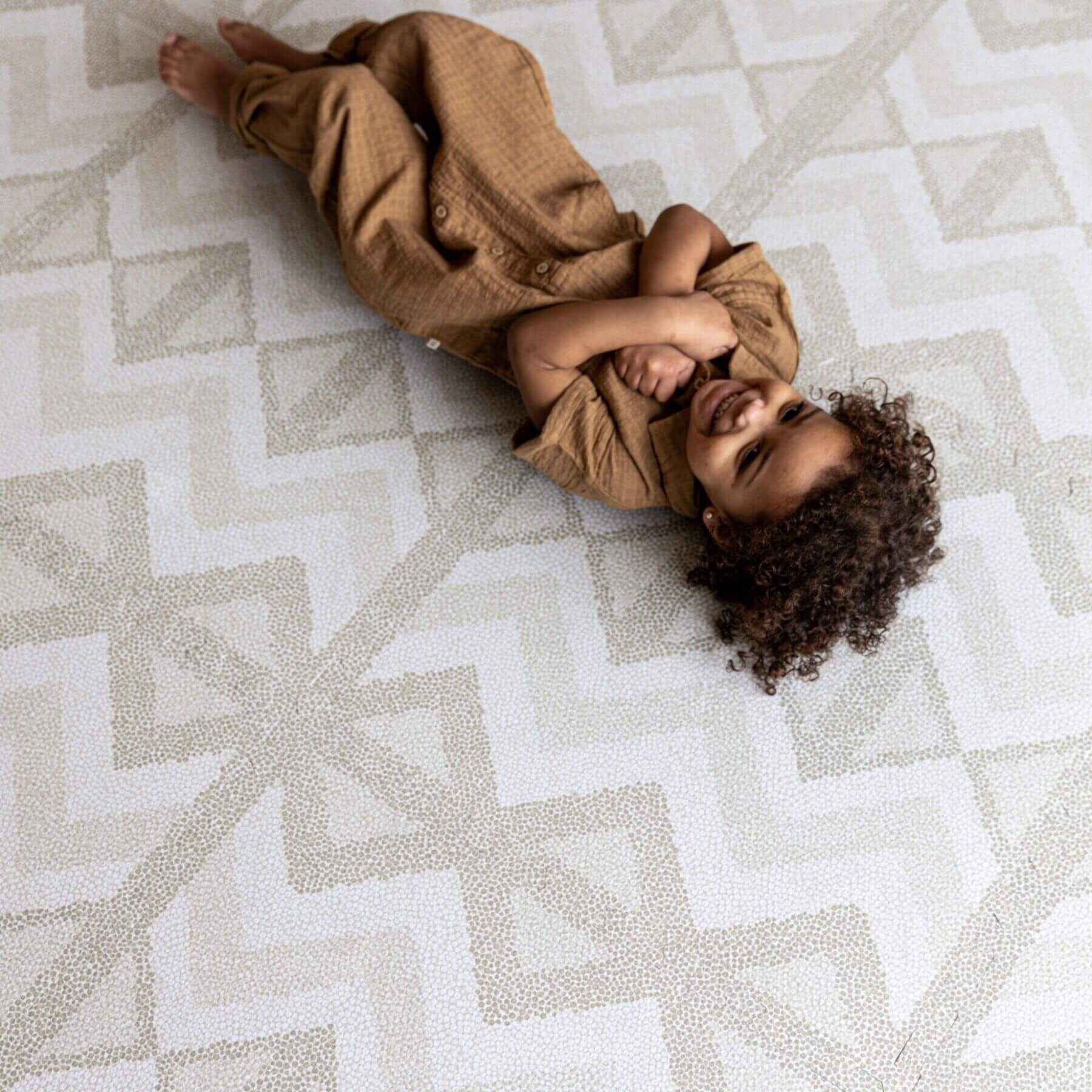 Child lying on Eeveve Kilim Play Mat, Feather Gray