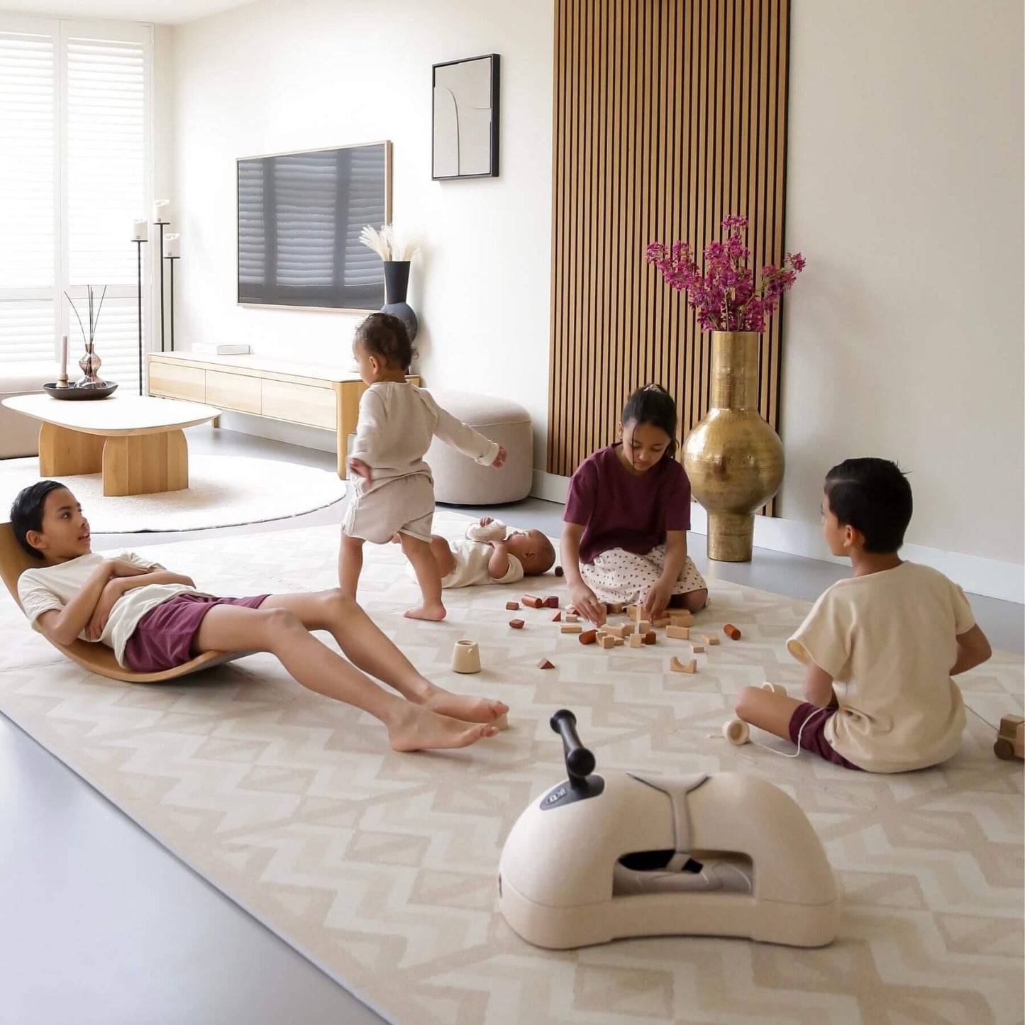 Family playing on Eeveve Kilim Play Mat - Soft Beige in a modern living room with a TV and decorative items.