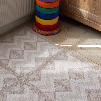 Eeveve Kilim Play Mat - Warm Pink on a wooden floor, next to a colorful cylindrical object.