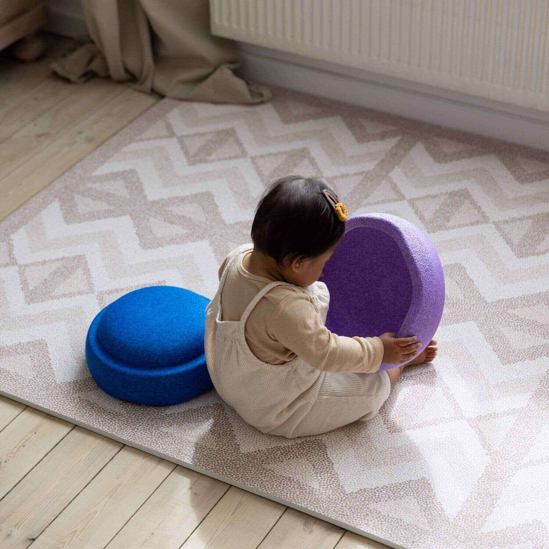 Child playing with a purple cushion on Eeveve Kilim Play Mat - Warm Pink
