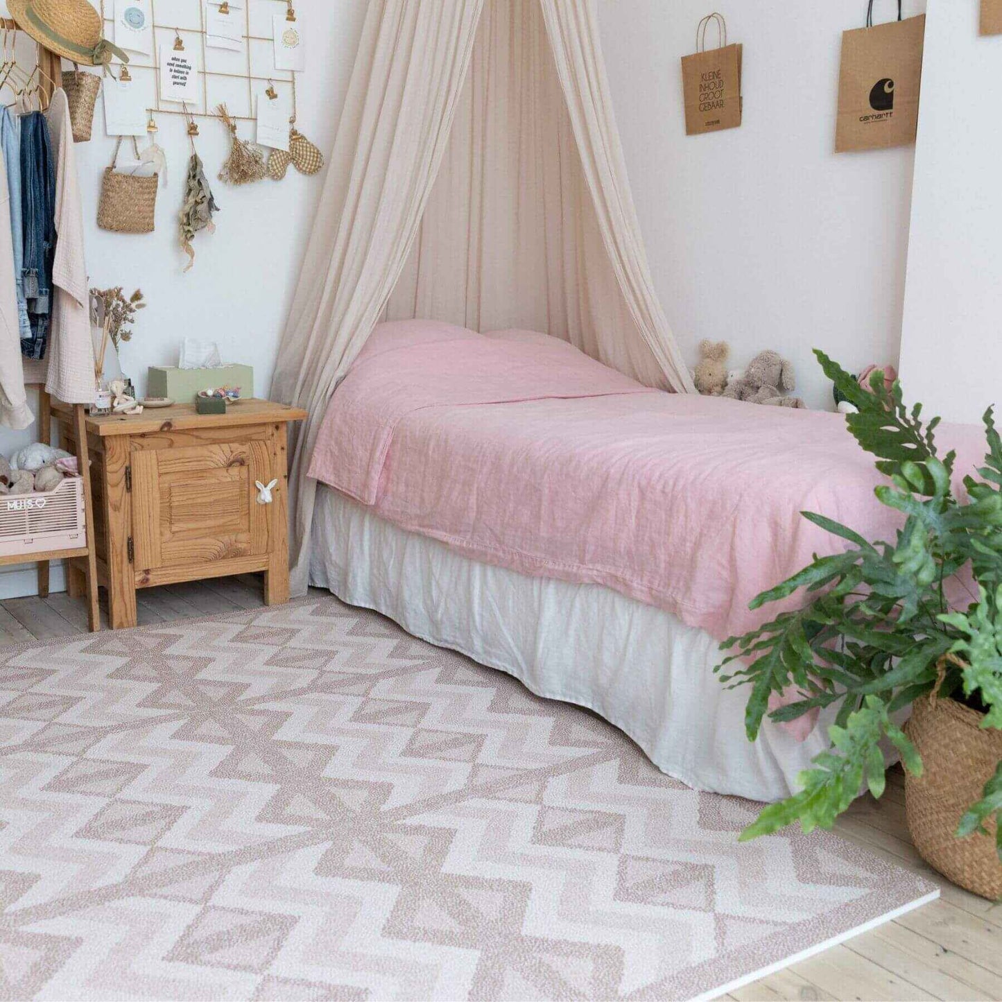 Bedroom with pink bedspread, wooden nightstand, and Eeveve Kilim Play Mat - Warm Pink.