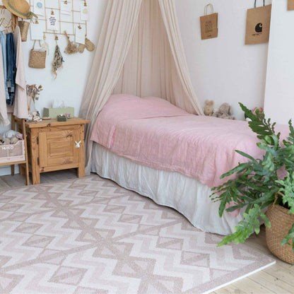Bedroom with pink bedspread, wooden nightstand, and Eeveve Kilim Play Mat - Warm Pink.