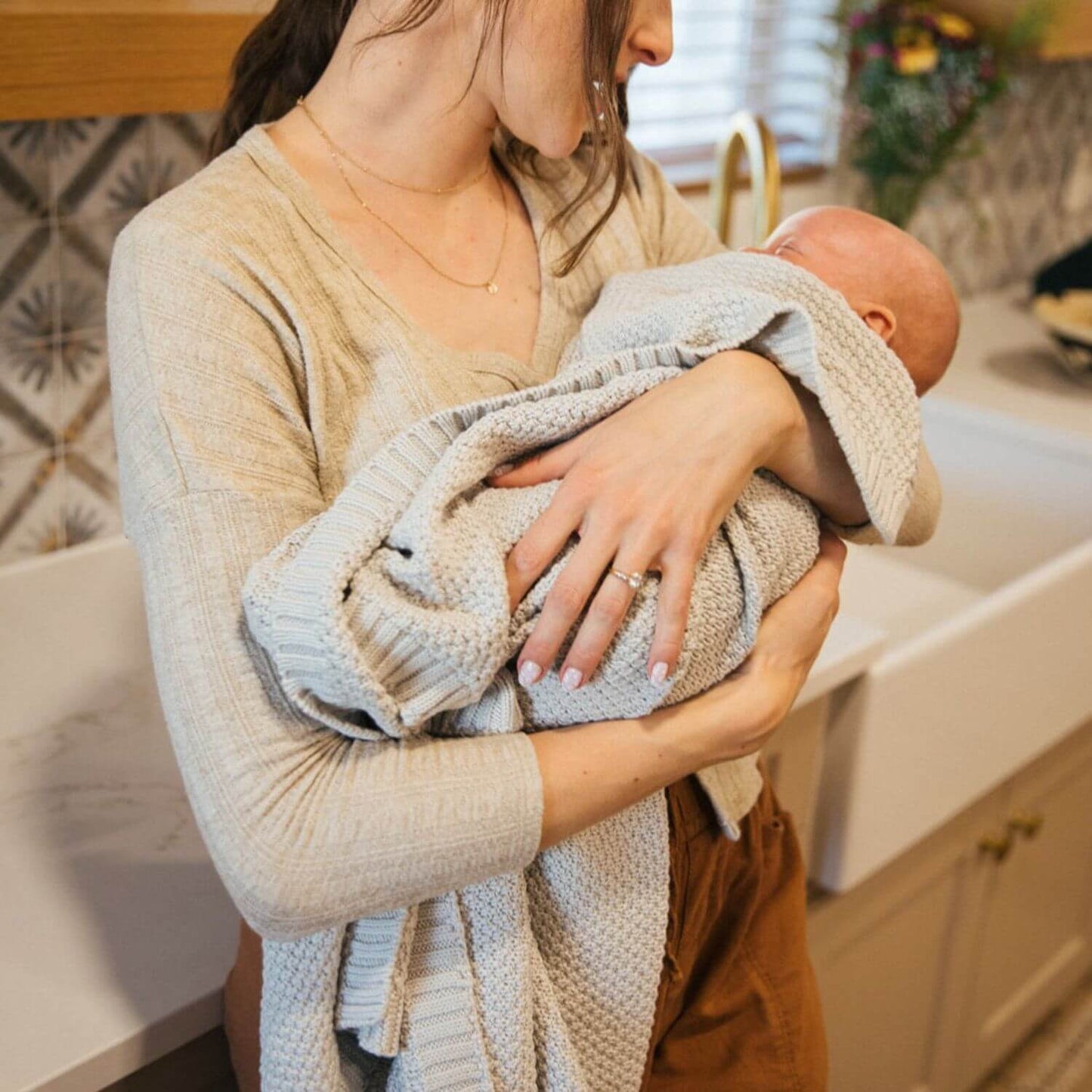 Mom Holding Baby Wapped in Plum+Sparrow Knitted Blanket Julep