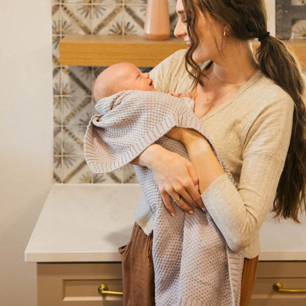 Mom Holding Baby Wrapped in Plum+Sparrow Knitted Blanket Thistle