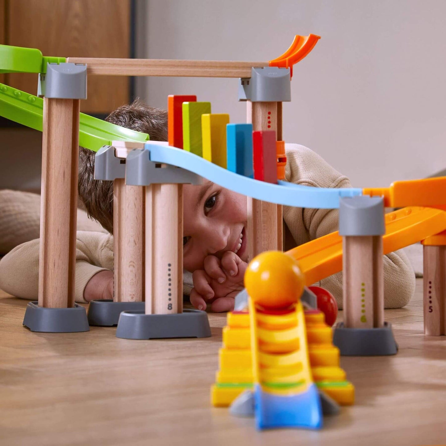 Child playing with HABA USA Kullerbu Melody Dominoes Set on a wooden floor.