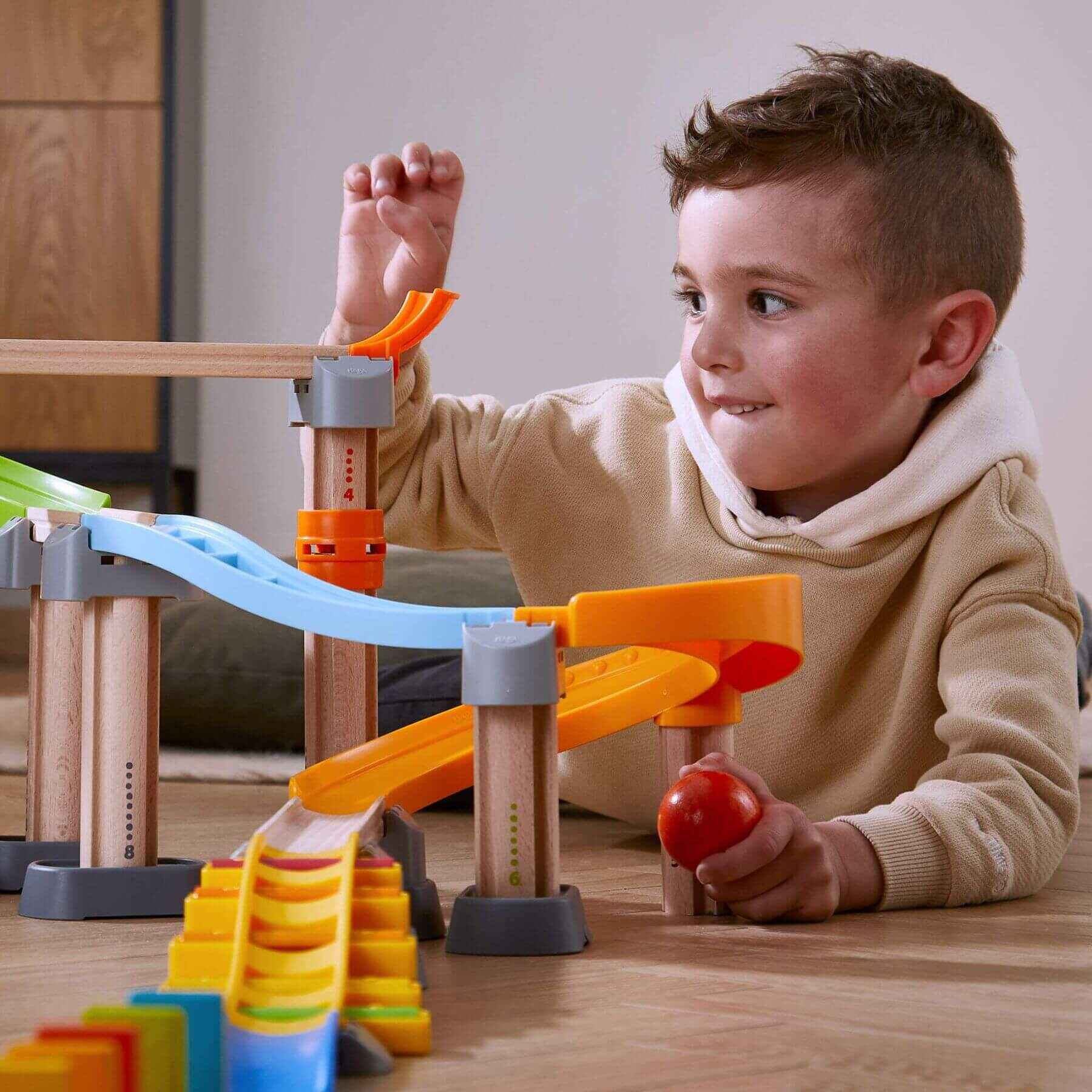 Child playing with HABA USA Kullerbu Melody Dominoes Set on a wooden table.