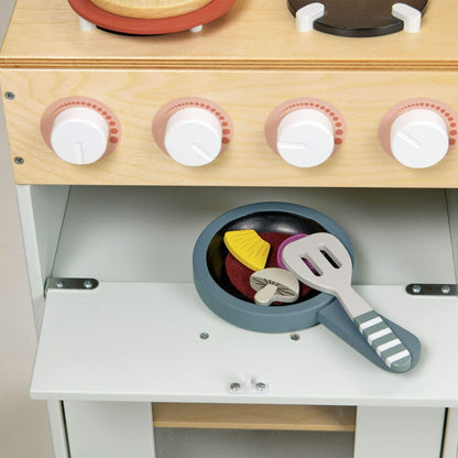 Wooden toy kitchen set with a stove, pan, and utensils on a neutral background