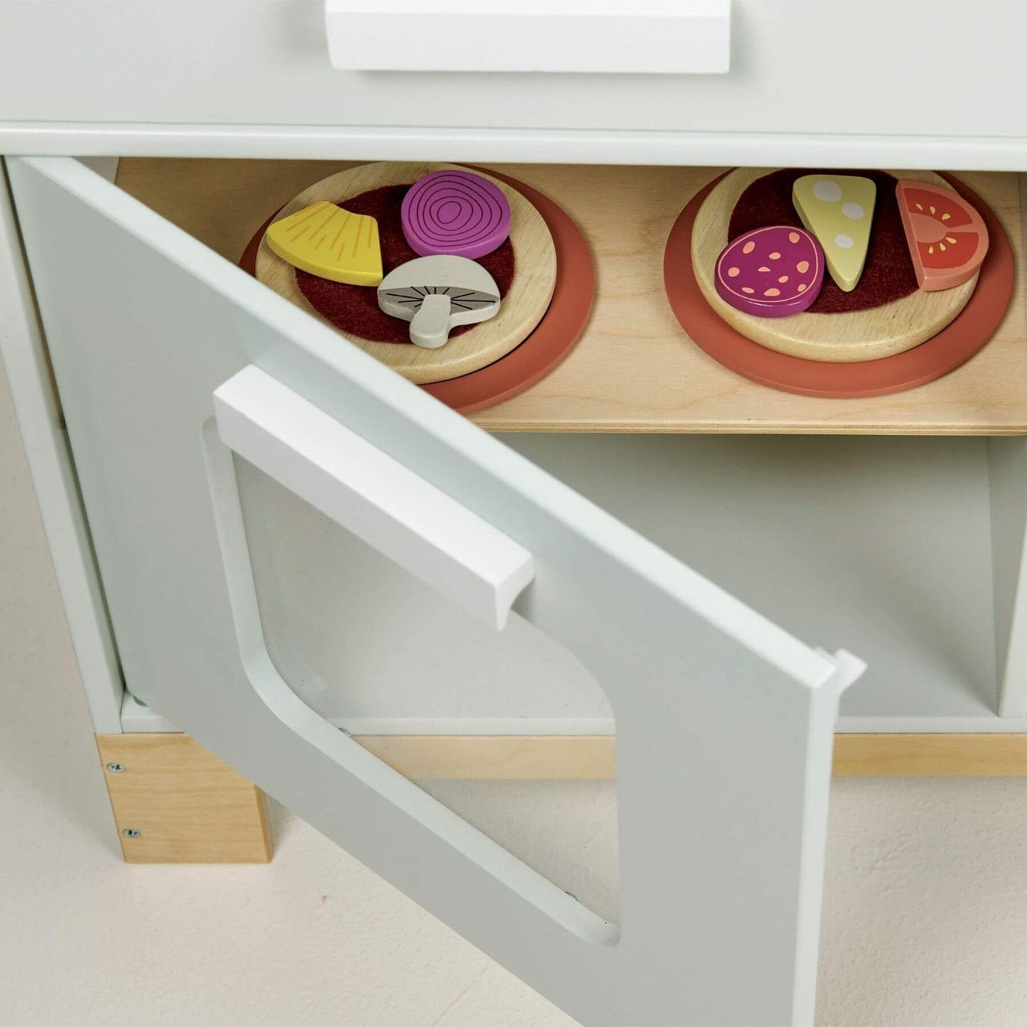 Wooden toy pizza set with colorful toppings on a white shelf.