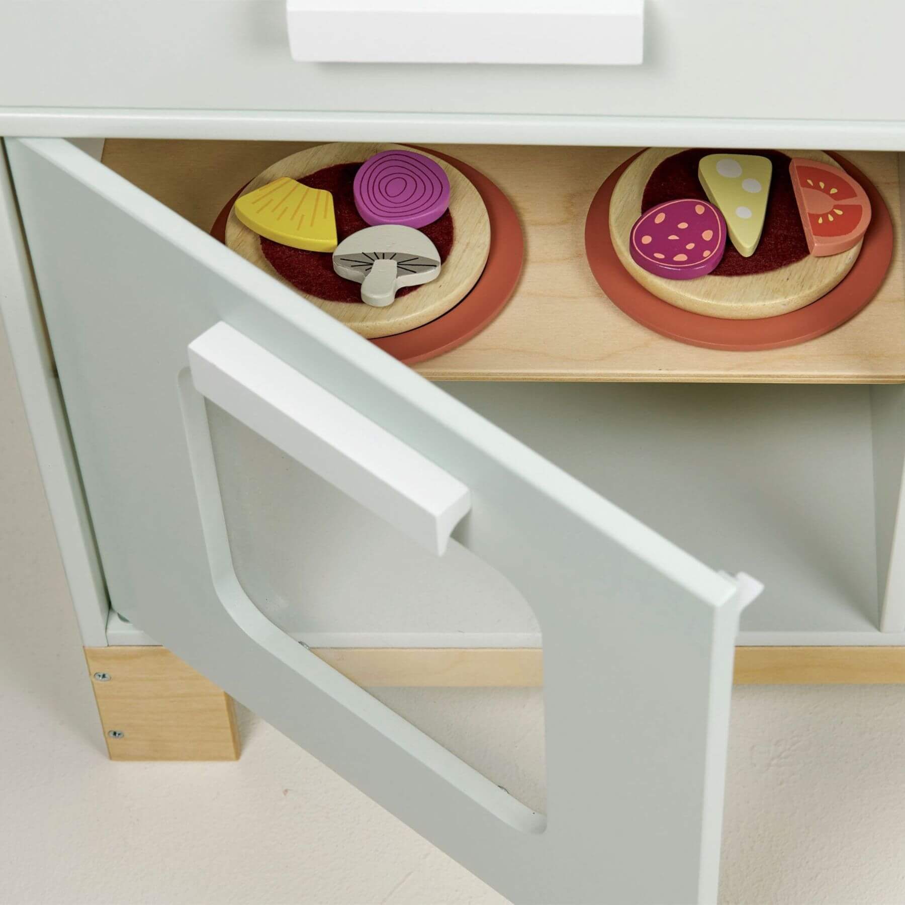 Wooden toy pizza set with colorful toppings on a white shelf.