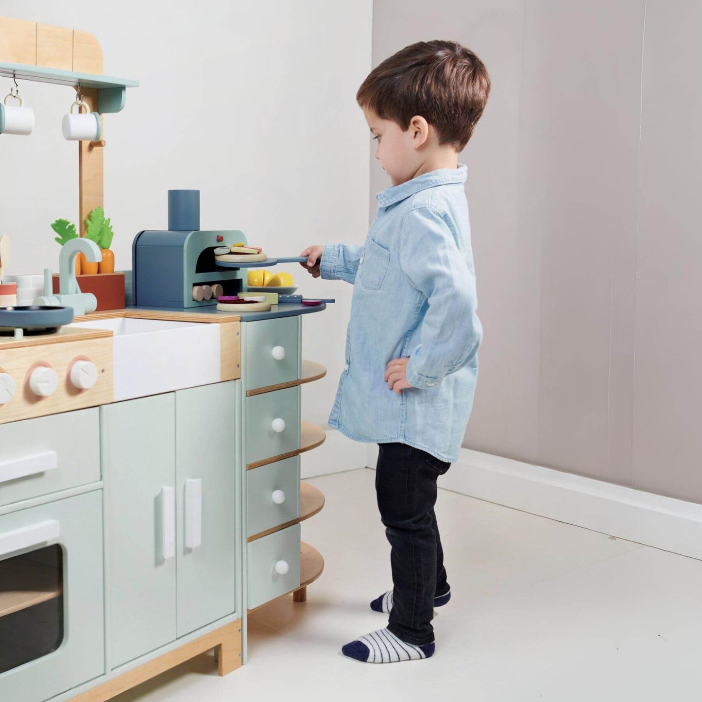 Child playing with Tender Leaf La Fiamma Grand Kitchen in a modern kitchen.