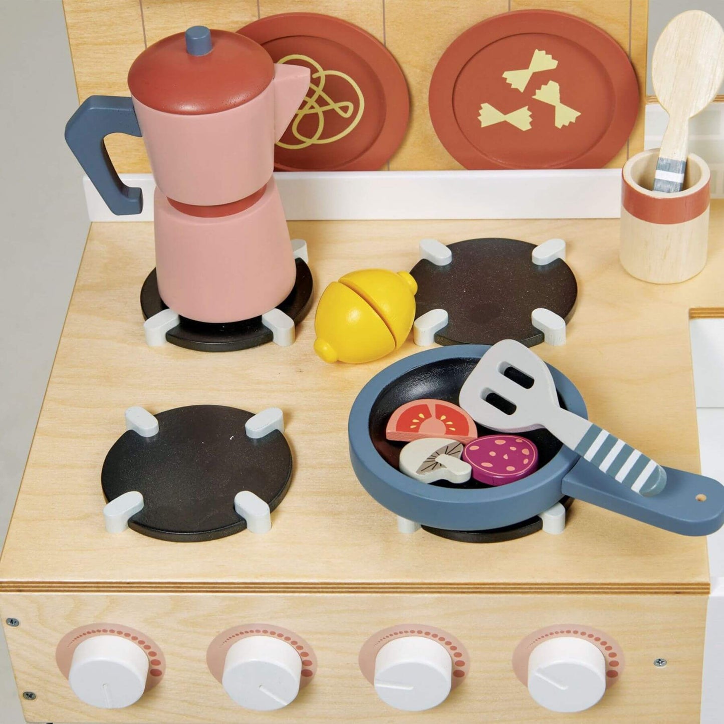 Wooden toy kitchen set with stove, pots, and utensils on a light background