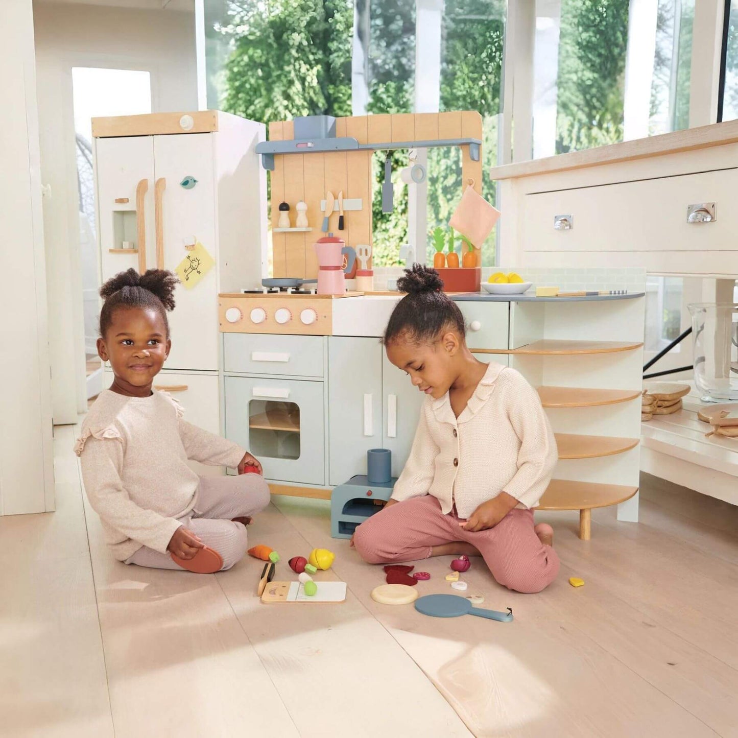 Two children playing with toys in a modern kitchen setup.