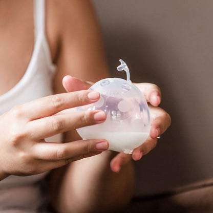 Person holding Haakaa Ladybug Silicone Milk Collector against a neutral background