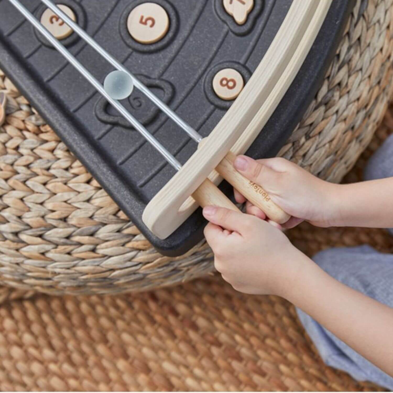 A close-up of a child's hands playing PlanToys Land The Planet
