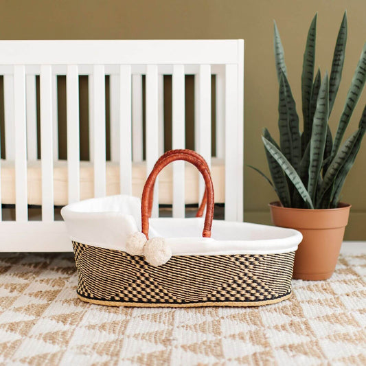 Plum+Sparrow Larksong African Moses Basket in front of White Crib