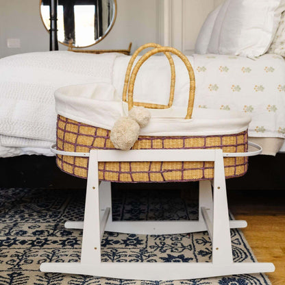 Lavender Grid African Moses Basket Vegan Handle with white bedding on a stand in a bedroom setting.