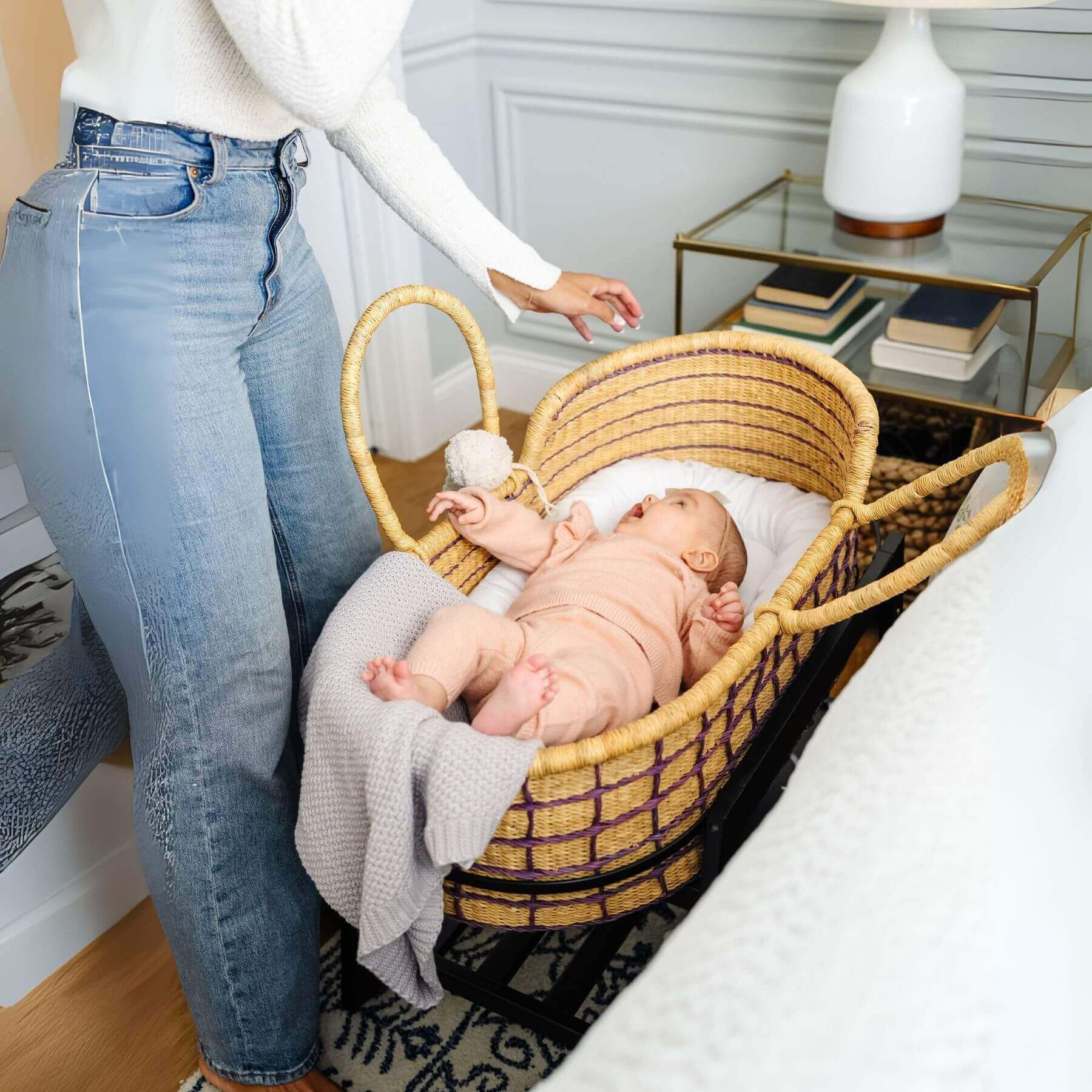Baby in Lavender Grid African Moses Basket Vegan Handle with a person standing nearby in a home setting