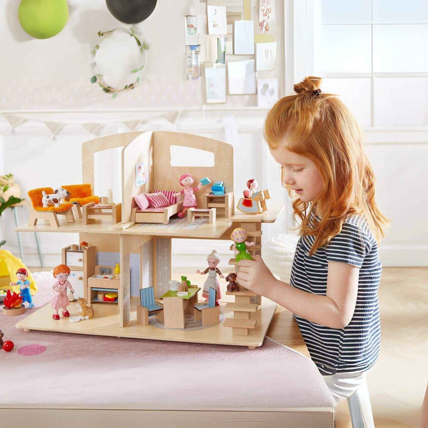 Child playing with Little Friends Dollhouse Town Villa with Furniture in a bright room.