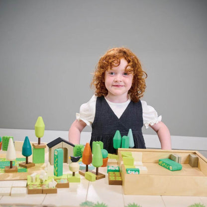 Child playing with Tender Leaf Little Garden Designer on a table against a gray background
