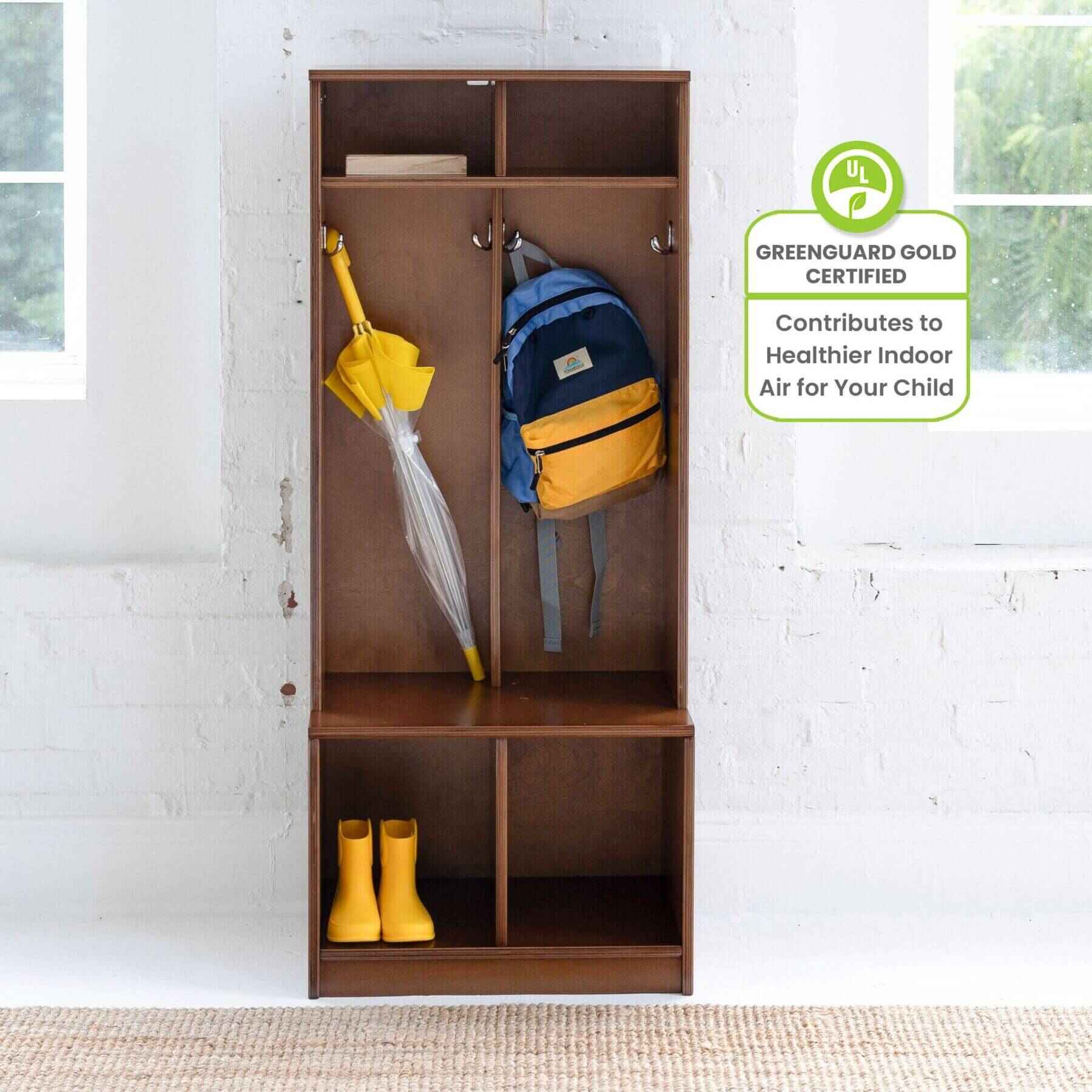Little Partners Learn 'N Store Cubby with backpack, umbrella, and boots against a white brick wall.