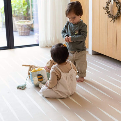 Two children playing on Eeveve Lucio Play Mat - Desert Sand with toys.