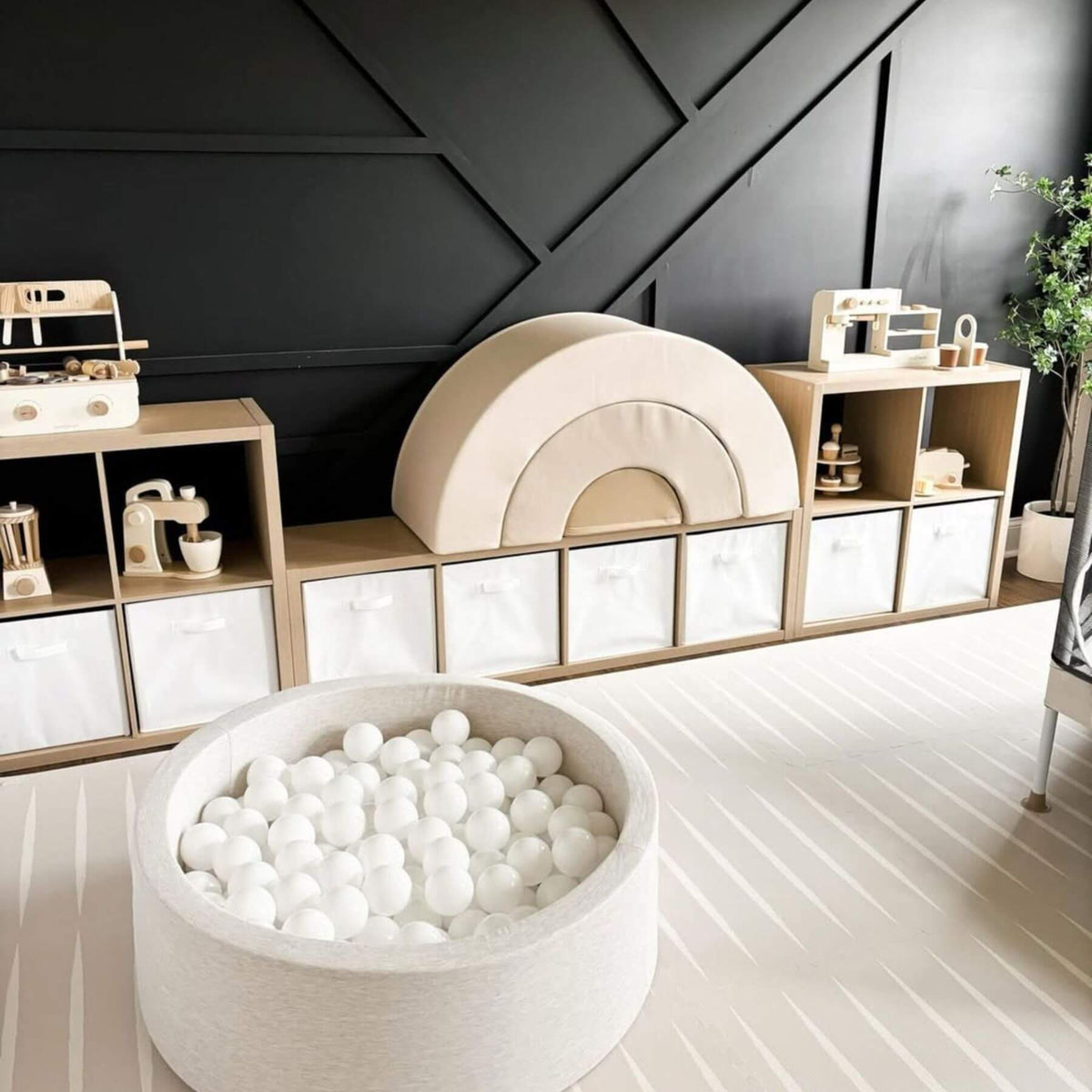 Children's playroom with a ball pit, shelves, and toys against a dark wall.