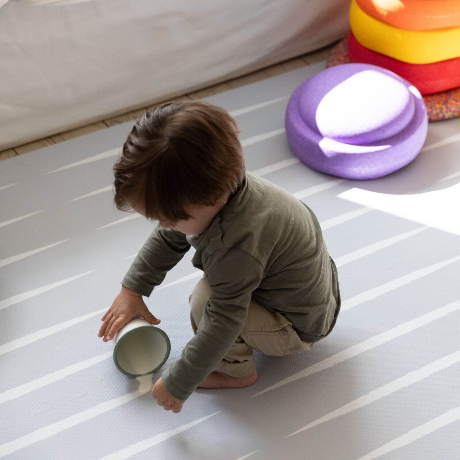 Child playing with a container on Lucio Play Mat Nordic Mist