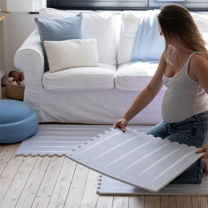 Woman assembling Lucio Play Mat Nordic Mist in a living room.