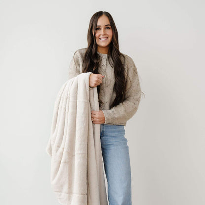 Woman holding Saranoni Lush Throw Blanket against a plain background