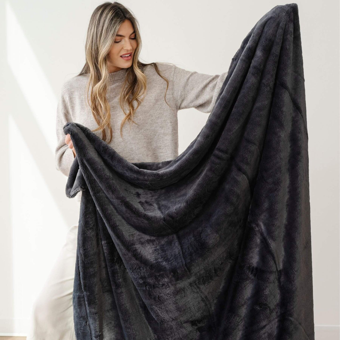 Woman holding a Saranoni Lush Throw Blanket against a white background
