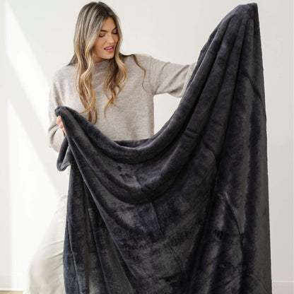 Woman holding a Saranoni Lush Throw Blanket against a white background