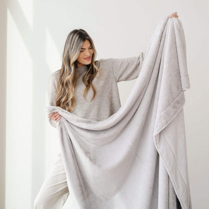 Woman holding a Saranoni Lush Throw Blanket Feather against a white background