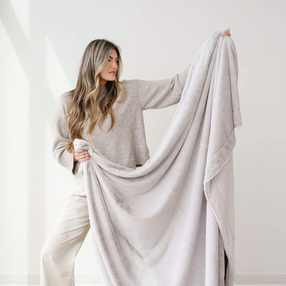 Woman holding a Saranoni Lush Throw Blanket Feather against a white background