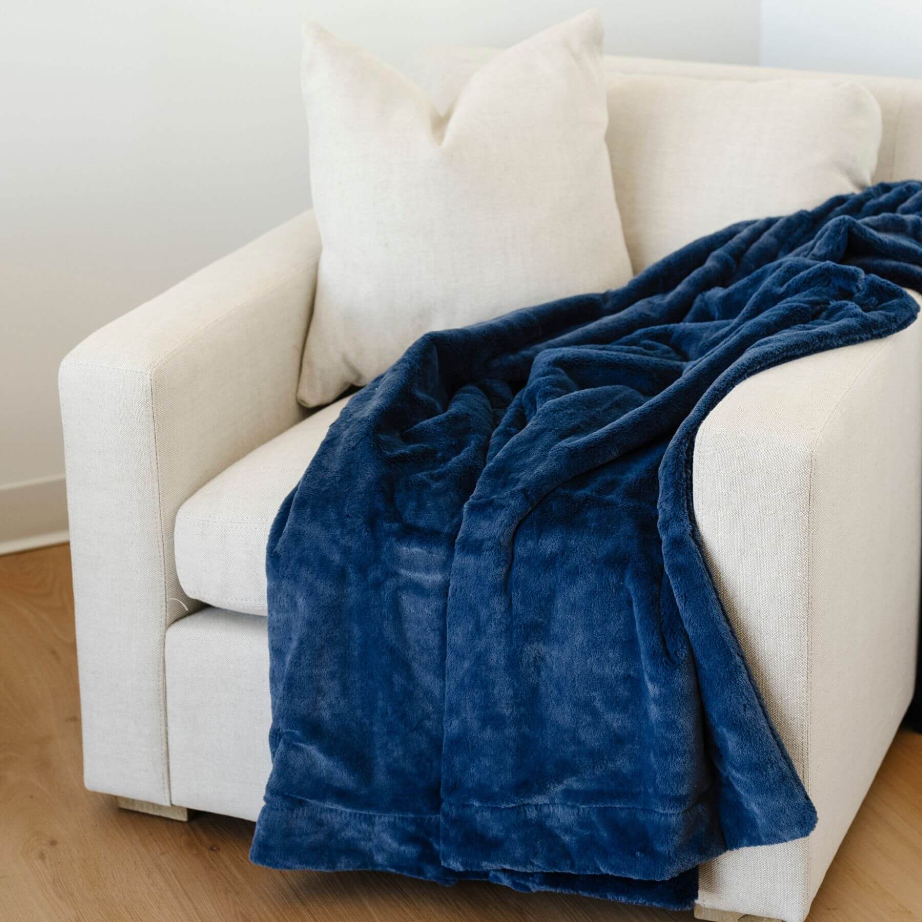 Saranoni Lush Throw Blanket Twilight draped over a white sofa in a room with wooden flooring.