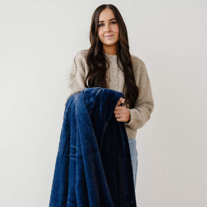 Woman holding a Saranoni Lush Throw Blanket Twilight against a plain background
