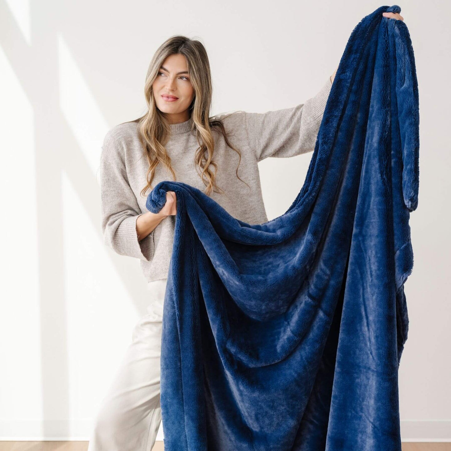 Woman holding a Saranoni Lush Throw Blanket Twilight in a bright room