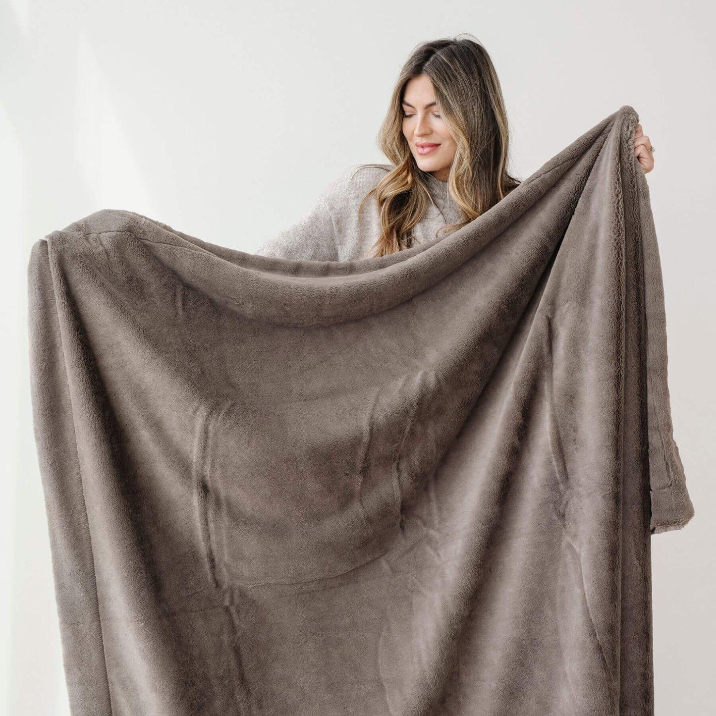 Woman holding a Saranoni Lush Throw Blanket Walnut against a white background