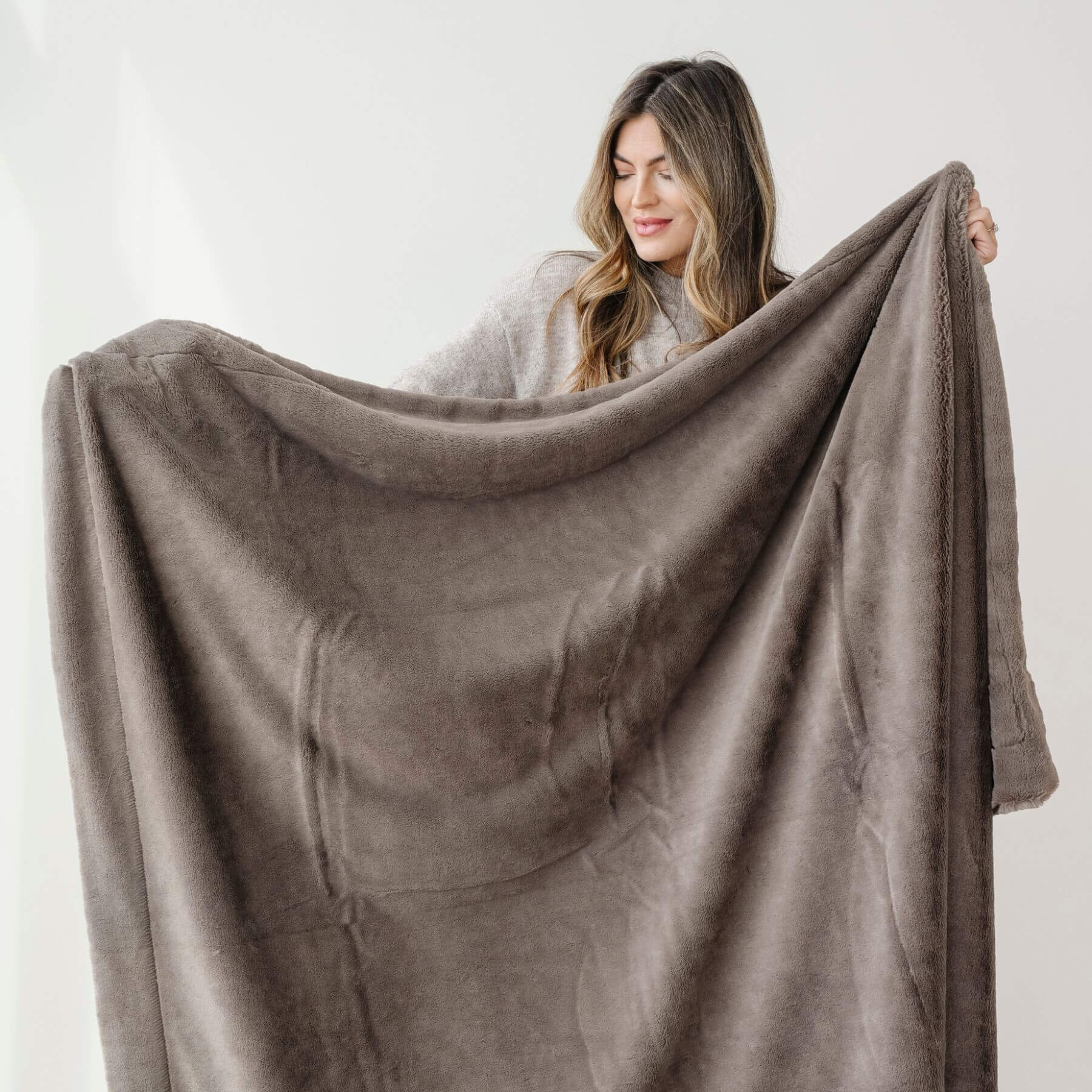 Woman holding a Saranoni Lush Throw Blanket Walnut against a white background