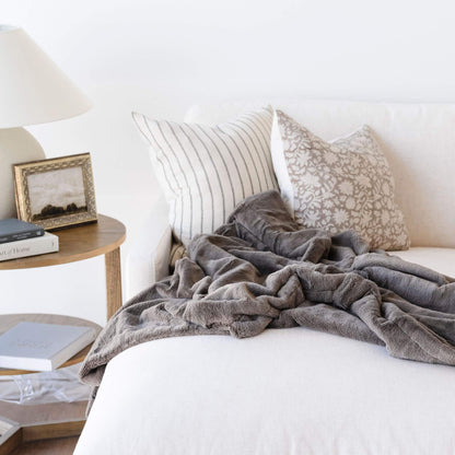 Saranoni Lush Throw Blanket Walnut draped over a white sofa with decorative pillows and a side table in the background.