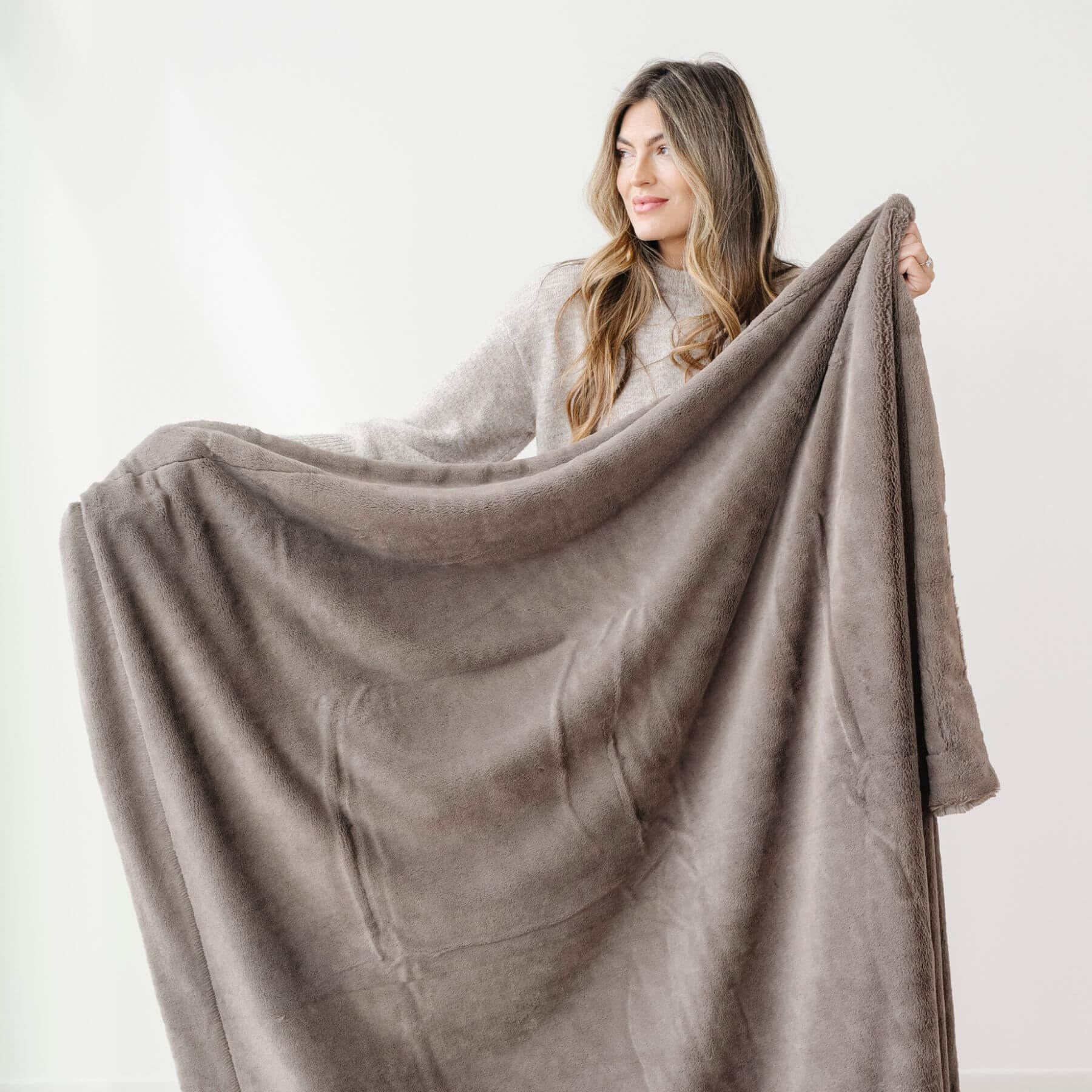 Woman holding a Saranoni Lush Throw Blanket Walnut against a white background